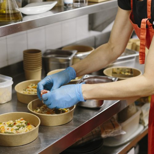 Cook preparing rice salads to take away. The containers used are compostable.