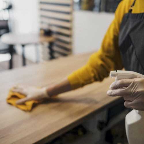 side-view-female-barista-cleaning-table-while-wearing-latex-gloves
